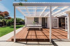 a white house with a wooden deck and pergolated roof