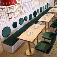 the tables are lined up against the wall with green velvet chairs and plates on them