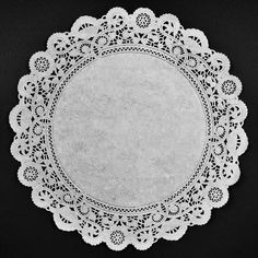 a white doily on a black background with an empty circle in the center, surrounded by small crocheted lace