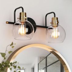 two light bathroom fixture with clear glass globes and gold accents on the vanity mirror