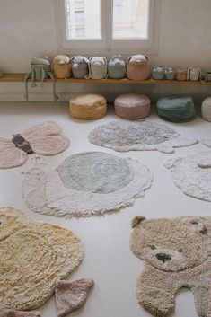 various rugs are arranged on the floor in front of a window with teddy bears