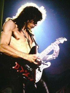 a man with long hair playing an electric guitar