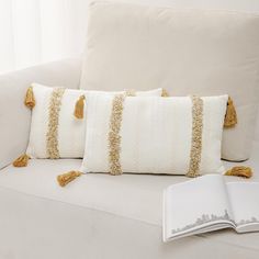 a white couch with yellow tassels and a book