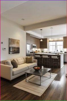 a living room filled with furniture and a kitchen in the backgroung area