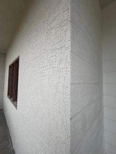 the corner of a building with a window on it's side and white walls