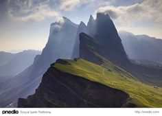 the mountains are covered in green grass and clouds