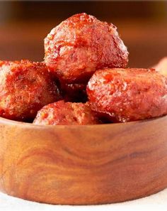 a wooden bowl filled with meatballs on top of a table