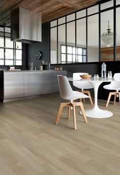 a modern kitchen with black walls and flooring, white chairs and an oval dining table