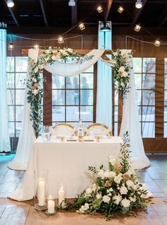 a table set up for a wedding with flowers and candles on the floor in front of it