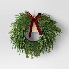 a christmas wreath with a red bow hanging from it's side on a wall