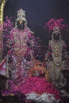 an elaborately decorated statue in front of a mirror with pink flowers on the floor