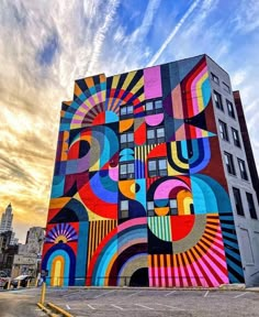 a large colorful mural on the side of a tall building in front of a cloudy sky