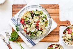 a salad with cucumbers, tomatoes and other vegetables on a wooden cutting board