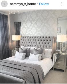 a bedroom with a bed, nightstands and mirror on the wall above it is decorated in silver and gray