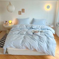 a bed with blue sheets and pillows in a room next to a checkered floor