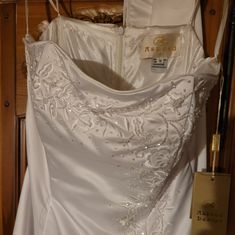 a white wedding dress hanging on a hanger in front of a closet with other items