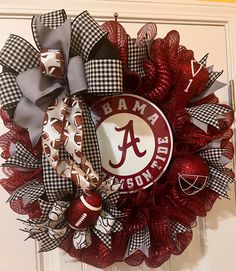 a wreath that has the letter a on it and is decorated with red, white and black ribbon