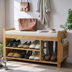 a wooden bench with shoes and purses on it in front of a white wall