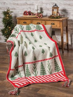 a christmas tree blanket is draped on a chair in front of a table with a potted plant