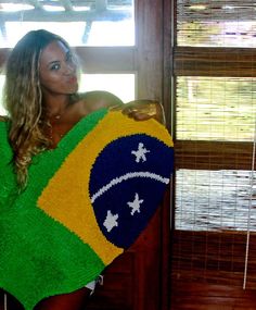 a woman is holding a towel with the flag of brazil on it in front of a window