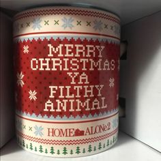 a christmas mug is sitting on the shelf next to some magnets that read merry christmas ya filthy animal home alone