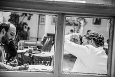 a man and woman sitting at a table in front of a window looking into each other's eyes