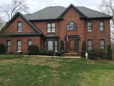 a large brick house sitting on top of a lush green field