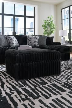 a living room filled with black and white furniture in front of large windowed windows