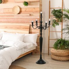 a bedroom with a bed, two candles and potted plants