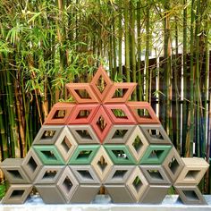 a sculpture made out of different colored blocks in front of bamboo trees