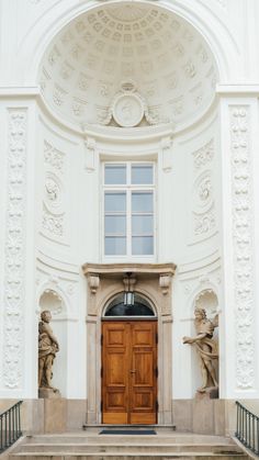 the entrance to an old building with statues on either side and a wooden door in front