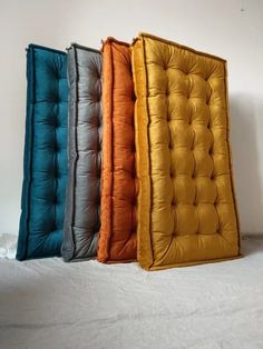 four different colors of the tufted mattress are lined up in a row on a white surface