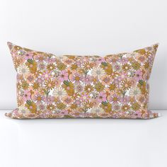 a pink and yellow floral pillow sitting on top of a white table