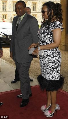 a woman in a black and white dress standing on a red carpet next to a man in a suit