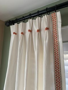 the curtains are hanging on the rod in front of the window, with an orange and white border