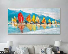 a living room with a white couch and painting on the wall above it that has colorful sailboats floating in the water