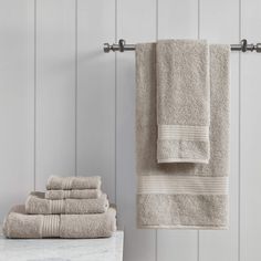 towels are lined up on a towel rack next to a marble table and white wall