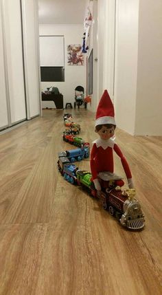 an elf riding a toy train on the floor