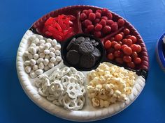 a paper plate filled with different types of food on top of a blue tablecloth