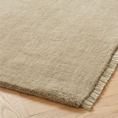 a beige rug with fringes on the floor in an area that is hard wood