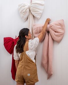 a woman is hanging some pink bows on the wall