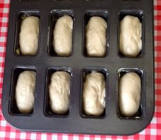 eight loaves of bread sitting in a muffin pan on a red and white checkered tablecloth