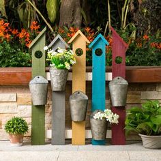 colorful birdhouses and flower pots in front of a brick wall