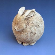 a ceramic rabbit sitting on top of a blue surface