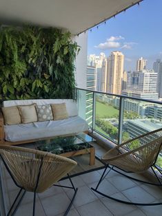 two chairs and a couch on a balcony with plants growing on the wall behind them