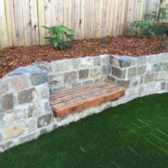 a wooden bench sitting next to a stone wall