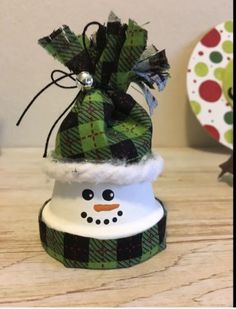 a snowman hat with a green and black plaid pattern on it sitting on top of a wooden table