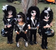 four children dressed up in black and white makeup, one holding a guitar while the other holds a pumpkin