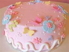 a pink cake sitting on top of a white plate covered in frosting and flowers