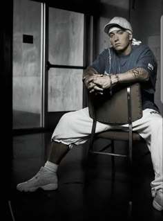 a man sitting on top of a chair in a black and white photo with his arms crossed